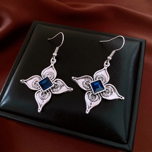 Détail de boucles d'oreilles fleurs argentées avec cristal bleu carré style rétro