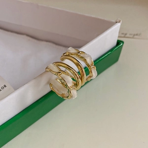 Detail of a gold metal ear cuff with cream fabric wrap on a green display box