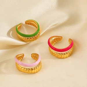Three gold adjustable enamel rings with striped texture on elegant silk fabric background