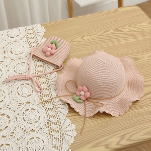 Close-up of pink straw hat and matching bag set with floral accents on lace cloth