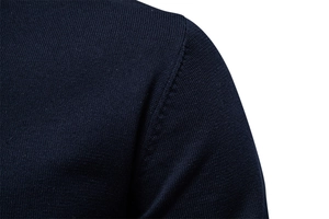 Detailed view of sleeve seam and fine knit texture on a dark blue V-neck sweater