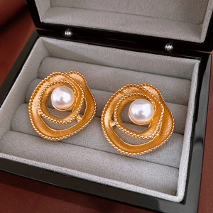 Close-up of vintage golden flower earrings with white pearl centers in a gray jewelry box