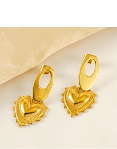 Détail de boucles d'oreilles cœur en acier titane doré sur tissu en soie