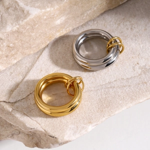 Polished gold and silver stainless steel rings on a natural stone textured background