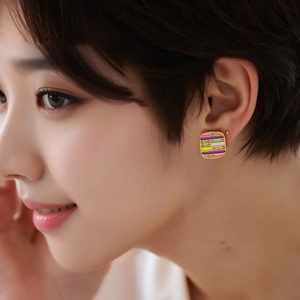 Close-up of a model wearing gold-plated square stud earrings with multi-color enamel stripes