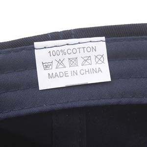 Detailed view of the wash care label on a 100% cotton baseball cap showing icons