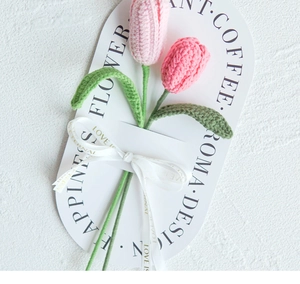 Close-up of pink crochet tulips with LOVE IS ETERNAL ribbon on white card paper