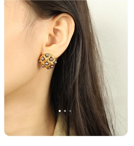 Detailed side view of a model wearing vintage gold mesh stud earrings with grey pearls