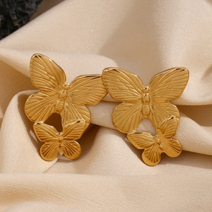 Macro view of gold butterfly earrings with double-layered hollow design on silk background
