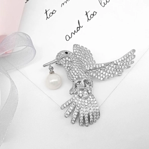 Elegant silver hummingbird brooch with white zircon pavé and dangling pearl on white card