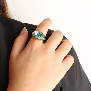 Detail of a large oval green sapphire ring with gold plating on a fashion model