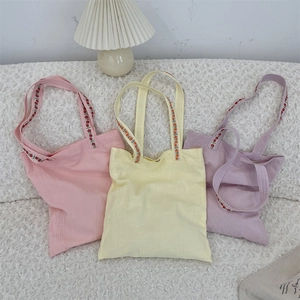Three colorful canvas tote bags featuring delicate floral embroidery on the shoulder straps