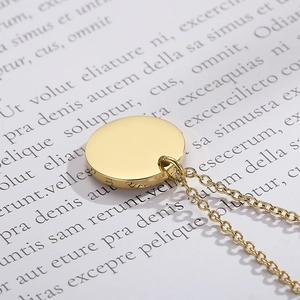 Vue macro d'un collier avec pendentif rond doré, finition polie et chaîne fine en métal