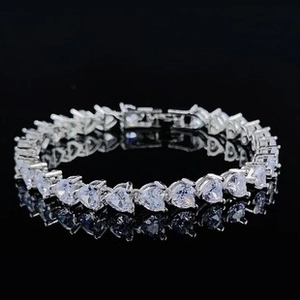 Detailed macro view of sparkling heart-shaped cubic zirconia tennis bracelet on black surface