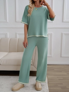 Detail view of mint green knitted set with cream-colored trim on short sleeves and wide pants
