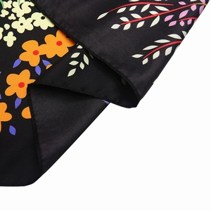 Detailed close-up of colorful floral patterns on black twill silk scarf fabric texture
