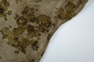 Detail shot of olive green velvet fabric with vintage floral patterns and glossy texture