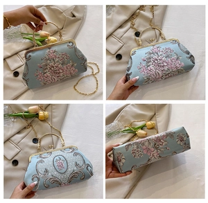 Detail view showing blue floral embroidery, metal clasp, and chain strap on handbag