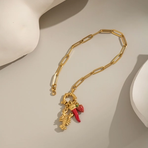Detail of gold paperclip chain with lobster, chili, and strawberry enamel charms