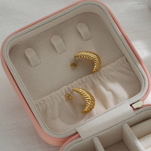 Close-up of golden croissant-style earrings displayed in a pink jewelry gift box