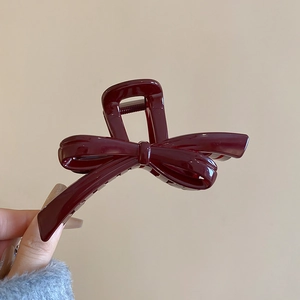 Detail of dark burgundy bow hair claw clip made of glossy resin with multi-teeth grip