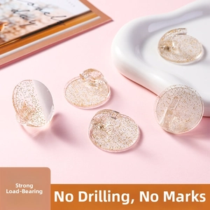 Detail of round transparent adhesive hooks with gold glitter for punch-free wall storage