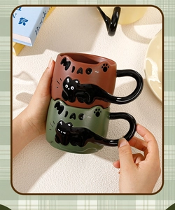 Detail of stacked ceramic mugs with 3D cat relief, cat tail handle and paw prints