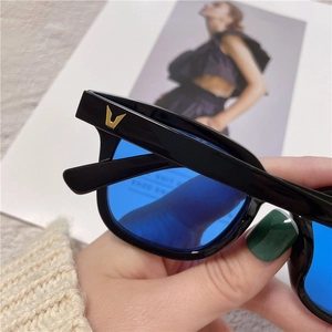 Detail of square black frame sunglasses with blue lenses and gold V logo on the temple
