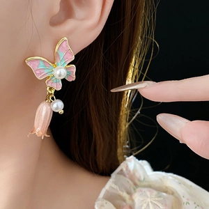 Dettaglio ravvicinato di orecchini a fiore vintage con smalto rosa e perle bianche
