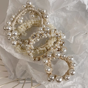 Close-up of three pearl hair ties with rhinestones arranged in a white wire basket