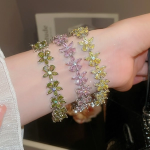Close-up of zircon flower bracelets in pastel green, purple, and yellow on wrist