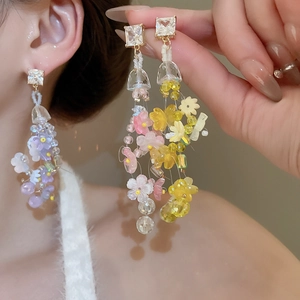 Close-up of dangling floral beaded earrings in purple and yellow on a model