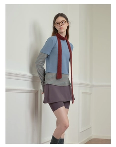Detail of a thin red knit wool scarf styled with a layered aesthetic and casual outfit