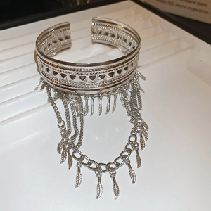 Détail d'un bracelet ouvert argenté vintage avec motifs géométriques et glands feuilles