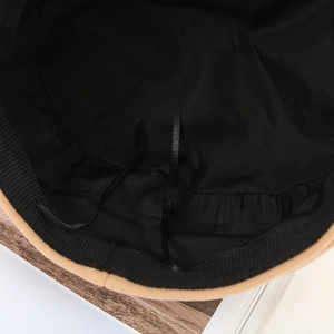 Detail view of the camel wool newsboy hat interior showing black lining and adjustable straps