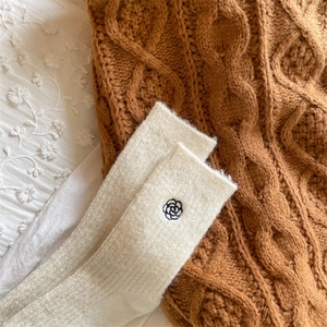 Close-up of winter thermal beige wool crew socks with delicate black flower embroidery