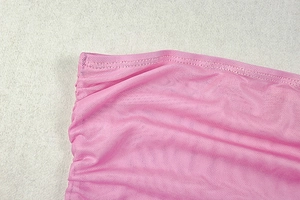 Dettaglio del tessuto a rete rosa con cuciture sottili e pieghe elasticizzate
