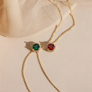Detail of round gold necklaces with emerald and ruby pendants on champagne silk fabric
