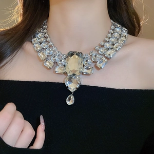 Macro shot of oversized heart and teardrop crystal pendant necklace on model neck