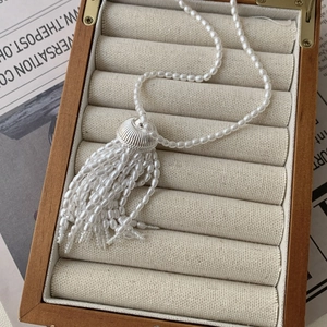 Detailed view of white pearl tassel pendant and textured silver metal cap on necklace