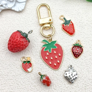 Stereo drip oil strawberry alloy pendants for DIY jewelry making on a beige background