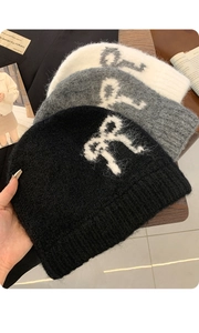 Close-up of fluffy knit beanies in black, grey, and white with bow jacquard patterns