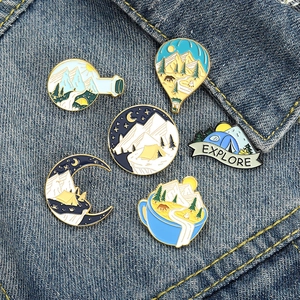 Set de pin's émaillés camping avec montagnes, tentes et montgolfières sur tissu denim