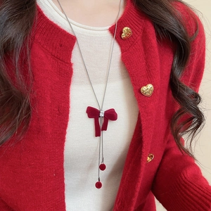 Close-up of red velvet bow pendant necklace with silver chain on model for winter styling