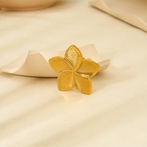 Macro shot of gold floral stainless steel ring on beige paper with soft lighting