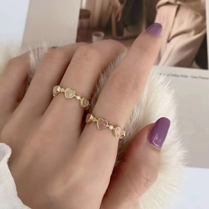 Close-up of gold adjustable heart rings with pink and white cat eye stones on a model