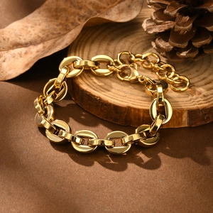 Detail of 18K gold-plated stainless steel Figaro bracelet on a rustic wood slice