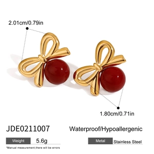 Détail de boucles d'oreilles nœud doré avec perles rouge foncé en acier inoxydable