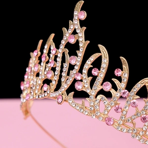 Detail of a vintage golden baroque crown featuring pink gems and white crystals