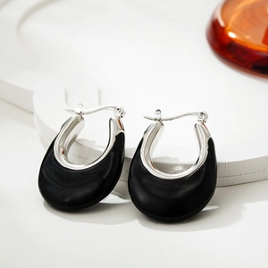 Detail view of U-shaped silver enamel earrings featuring a modern croissant buckle design